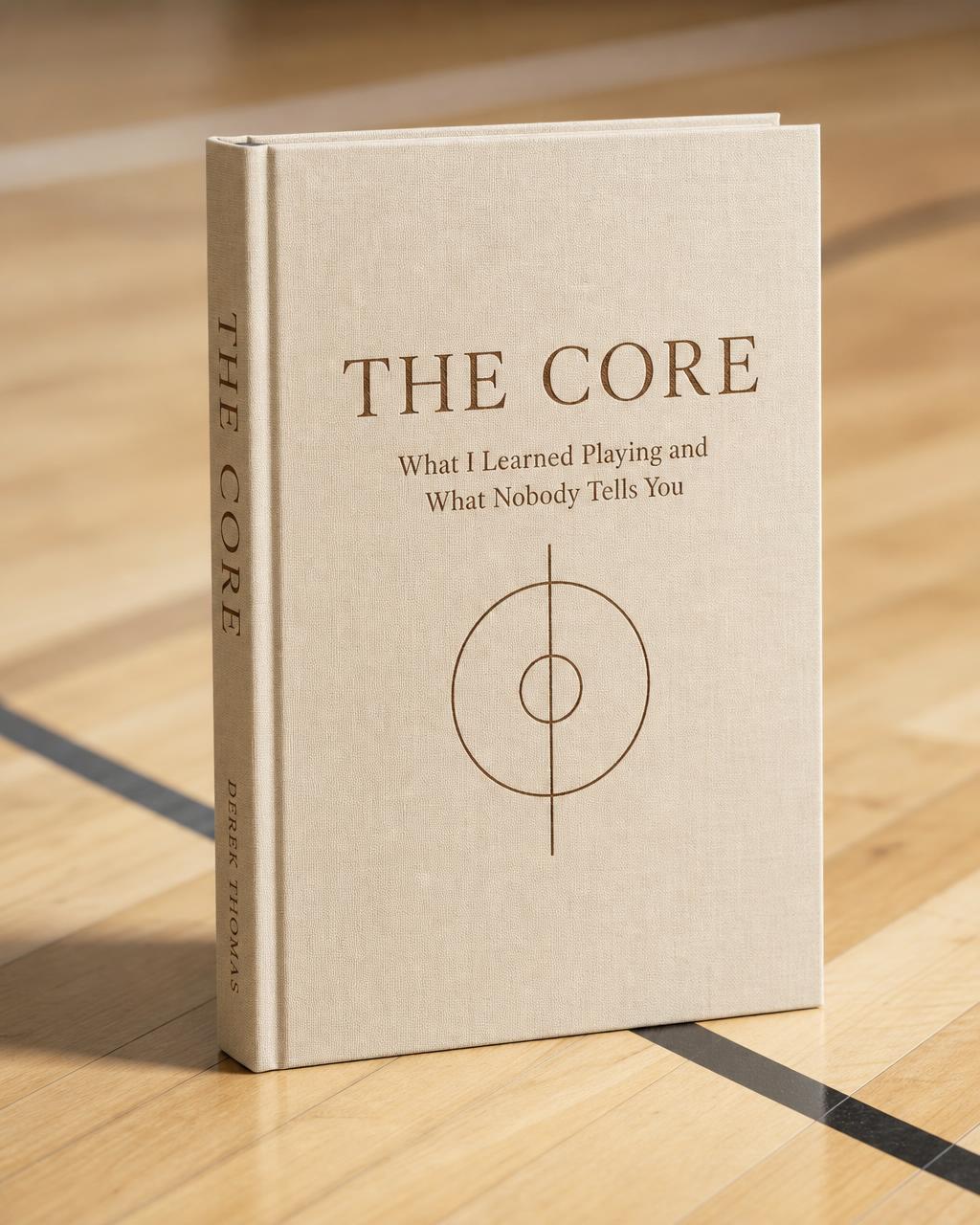 THE CORE book — cream linen hardcover standing on a maple basketball court